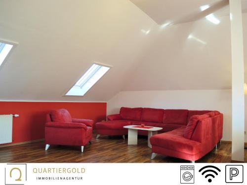 a living room with a red couch and two chairs at Monteurwohnung mit Stil in Schwarzheide
