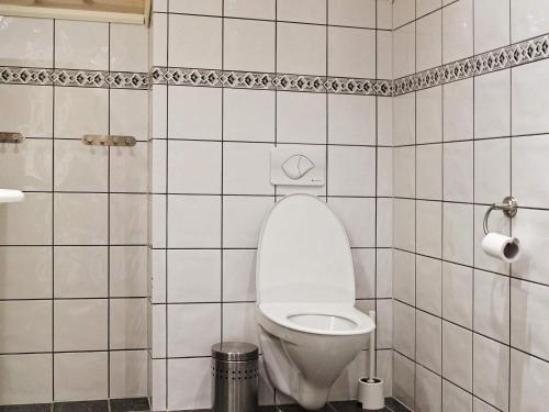 a bathroom with a toilet in a white tiled wall at 11 person holiday home in hebnes in Hebnes