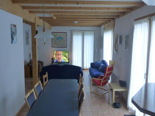 a living room with a table and a woman on a television at Chalet in Saint-Jean near Ski Lift in Saint-Jean-d'Aulps
