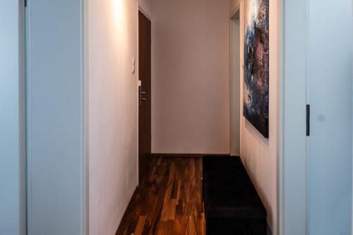 a hallway with white walls and wooden floors and a door at 3 room apartment with balcony City center east in Mönchengladbach
