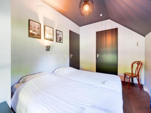 a bedroom with a white bed and a chair at Atmospheric country house in Asten on a golf course in Asten