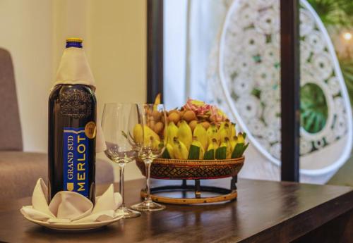 a bottle of wine and a basket of fruit on a table at Angkor Land House in Phumĭ Réach Born