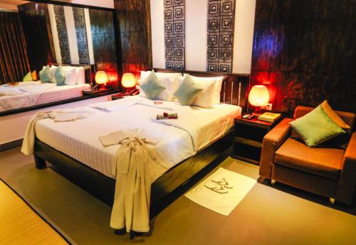 a bedroom with a large bed and a chair at Angkor Land House in Phumĭ Réach Born