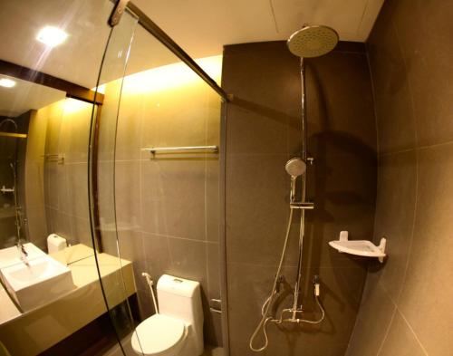 a bathroom with a shower with a toilet and a sink at The Bangkok Major Suite in Bangkok