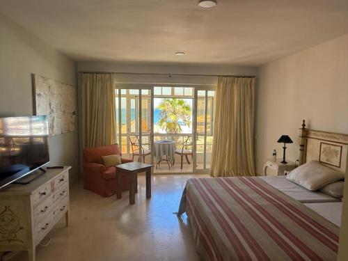 a bedroom with a bed and a television and a balcony at Apartamento Puerto Sotogrande Marina in Sotogrande