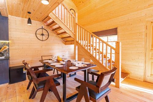 a dining room with a table and chairs and a staircase at SaffronStays The Woods - Sal Villa in Dehradun