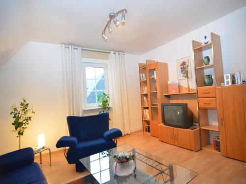a living room with a blue chair and a tv at Apartment near ski area in Wehrstapel in Sauerland in Meschede
