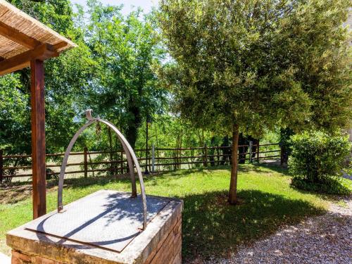 a stone fountain in a yard next to a fence at Scenic Apartment in Casole d'Elsa with Pool in Casole dʼElsa