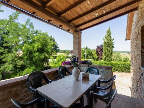 a table and chairs on a patio with a large window at Scenic Apartment in Casole d'Elsa with Pool in Casole dʼElsa