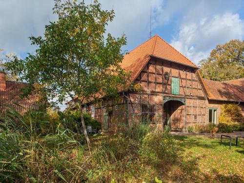an old stone building with a red roof at Historic Farmhouse in Hohnebostel with Garden near Lake in Langlingen