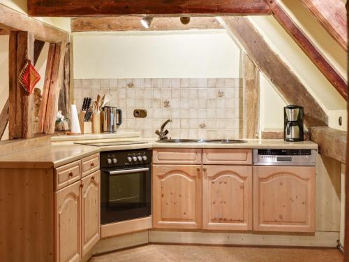 a kitchen with wooden cabinets and a stove top oven at Historic Farmhouse in Hohnebostel with Garden near Lake in Langlingen