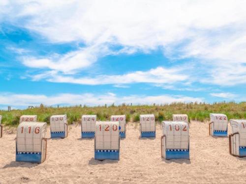 a row of beach chairs on a sandy beach at Charming Apartment in Oldenburg in Holstein with Terrace in Oldenburg in Holstein
