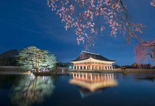 a building with a reflection in the water at night at Queen Bed 5 #10 people # Airport Railway Station # Triple Station # Hong dae # seoul #3room # DMC # bnb in Seoul
