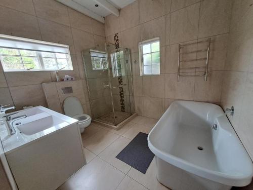 a bathroom with a tub and a sink and a toilet at Fiore Guest Accommodation in Greyton