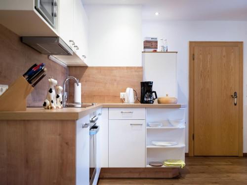 Una cocina con gabinetes blancos y un fregadero. en Cozy feel good holiday apartment in Leogang, en Leogang