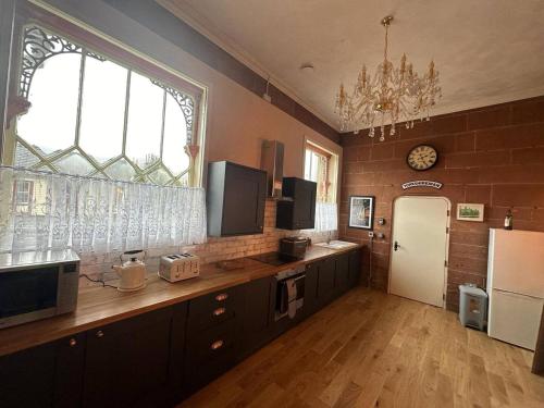 a kitchen with a counter and two windows and a refrigerator at Station Cottage 4 Bed Cottage Ev Free Parking in Langwathby