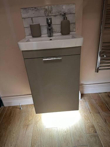 a sink in a bathroom with a light under it at Station Cottage 4 Bed Cottage Ev Free Parking in Langwathby
