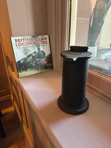a black podium sitting on a window sill next to a book at Station Cottage 4 Bed Cottage Ev Free Parking in Langwathby