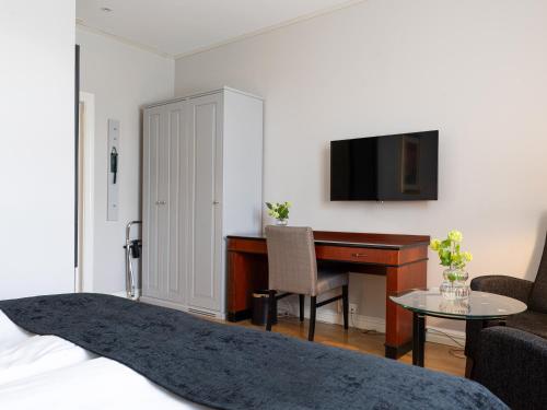 a bedroom with a bed and a desk and a computer at Elite Stadshotellet Västerås in Västerås