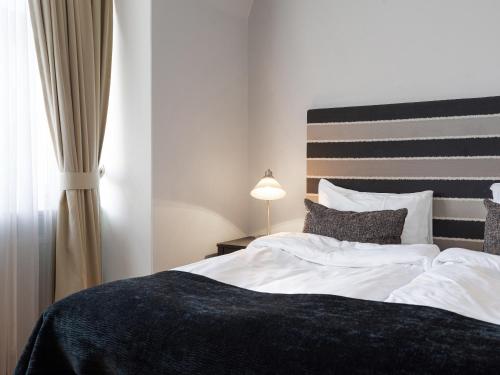 a bedroom with a large bed with white sheets and a lamp at Elite Stadshotellet Västerås in Västerås