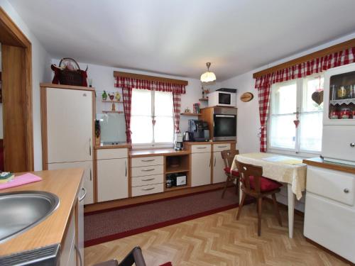 a kitchen with white cabinets and a table with a sink at Chalet Bamberg near Ski Lift & Slope in Bramberg am Wildkogel