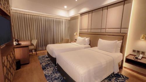 a hotel room with two beds and a desk at Aston Sentul Lake Resort & Conference Center in Bogor