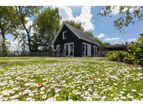 Una casa negra con muchas flores en el patio. en Family house with an ideal location, private terrace, garden and sauna, en Vrouwenpolder