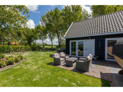 un patio con un grupo de sillas y una casa en Family house with an ideal location, private terrace, garden and sauna, en Vrouwenpolder