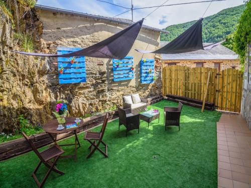 a patio with a table and chairs on grass at Riverside Rustic Retreat in La Omañuela
