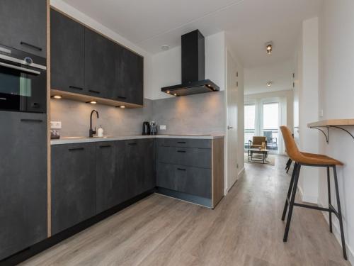 a kitchen with black cabinets and a wooden floor at Unique apartment, located on the Oosterschelde and marina of Sint Annaland in Sint Annaland