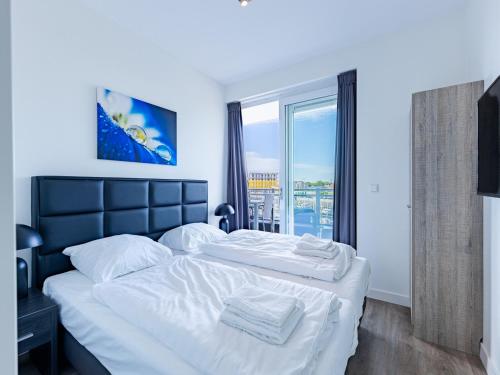 a bedroom with a large bed with white sheets and a window at Unique apartment, located on the Oosterschelde and marina of Sint Annaland in Sint Annaland