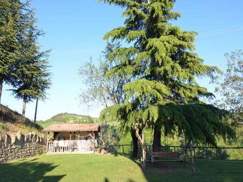 a tree in a yard with a house in the background at Apartment in quiet and green environment with swimming pool in Modigliana