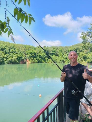 a man holding a fishing pole in front of a lake at Lake View Resort in Ban Nam Rop