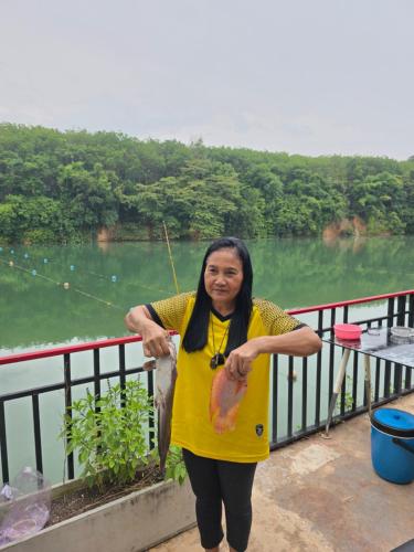 a woman standing on a balcony holding a fish at Lake View Resort in Ban Nam Rop