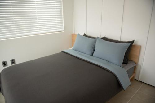 a bedroom with a bed with blue pillows and a window at Wonderpool pension in Jeju