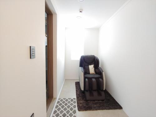 a black chair sitting in a hallway next to a door at Wonderpool pension in Jeju