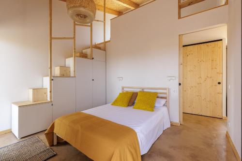 ein Schlafzimmer mit einem Bett mit gelben Kissen darauf in der Unterkunft Empordà Soul, casa rural moderna con piscina in San Miguel de Fluviá