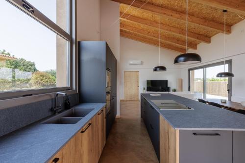 eine Küche mit einer großen Theke und einem großen Fenster in der Unterkunft Empordà Soul, casa rural moderna con piscina in San Miguel de Fluviá