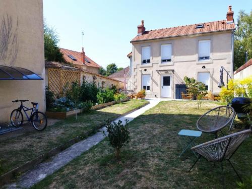 a yard with two chairs and a bike in front of a house at Maison Sorbier, Appartement 1 in Nevers