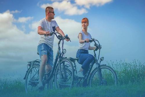 a man and a woman riding bikes in a field at Holiday home in Osieki near a lake in Osieki