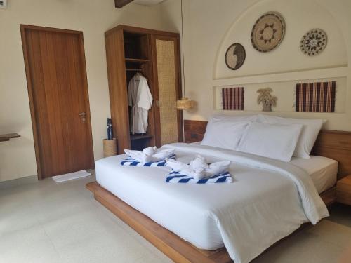 a bedroom with a large white bed with towels on it at Agusta Villas in Uluwatu