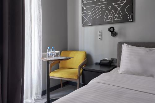 a bedroom with a table and a yellow chair next to a bed at Sapiens Hotel in Tashkent