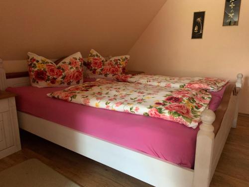 a bed with a pink and white comforter and pillows at Apartment in Luckaitztal-Gossda with parking space in Zwietow