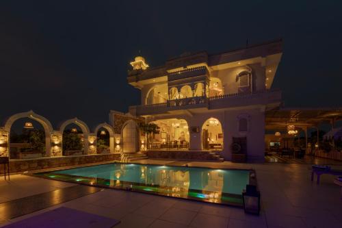 a villa with a swimming pool at night at SaffronStays Raj Reverie in Jaipur