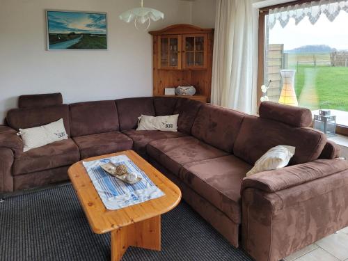 a living room with a brown couch and a coffee table at Geraeumige Ferienwohnungen mit eigener Terrasse, Neßmersiel in Neßmersiel