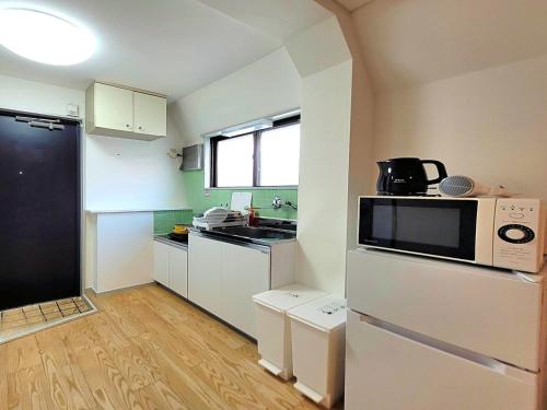a small kitchen with white cabinets and a microwave at Liberty Shinjuku House in Tokyo