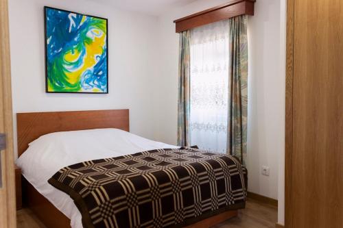 ein Schlafzimmer mit einem Bett und einem Gemälde an der Wand in der Unterkunft Casa da Zurja in Guarda