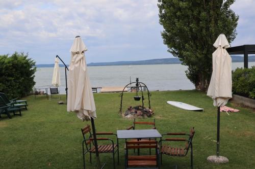 a group of tables and chairs with umbrellas and a playground at Vízparti apartmanok in Szántód