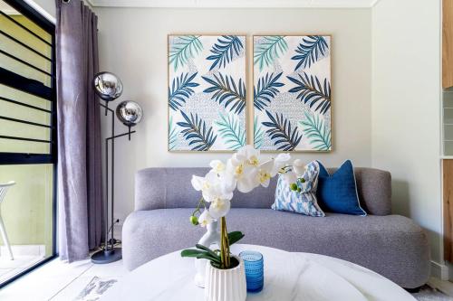 a living room with a couch and a vase with flowers at #AlimamaSpaces Rob's GreenPark in Boksburg
