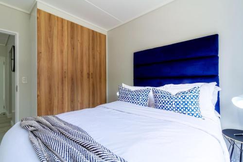 a bedroom with a white bed with blue and white pillows at #AlimamaSpaces Rob's GreenPark in Boksburg